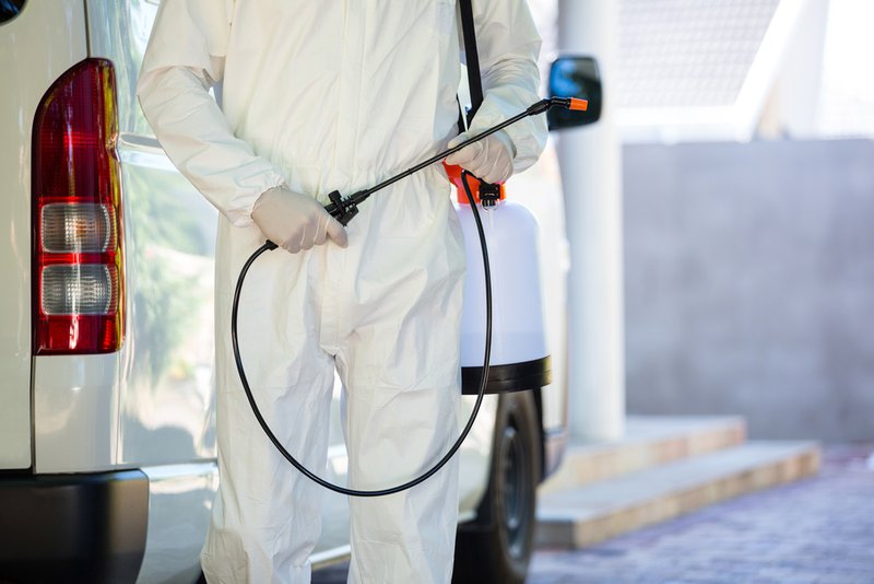 Mid section of pest control man standing next to a van on a street